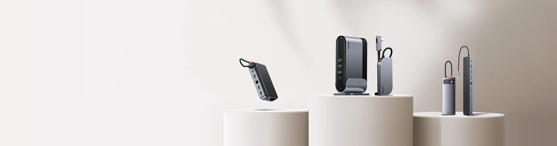 Electronic devices on cylindrical white stands against a light beige background