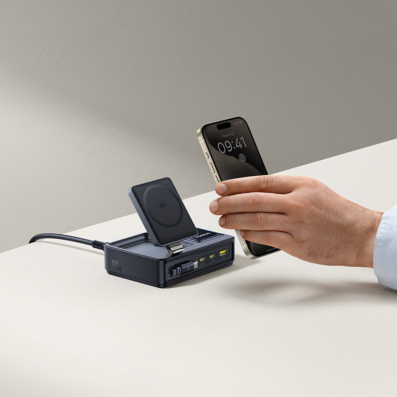 Person using a smartphone with a charging station on a light surface