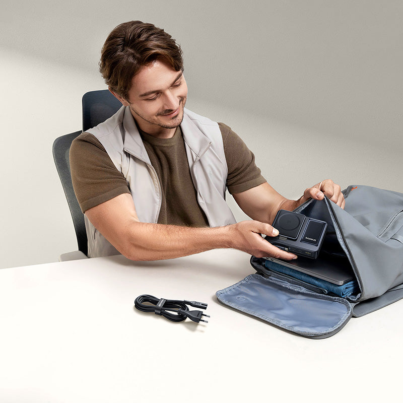 Man organizing a camera and accessories on a table with a neutral background