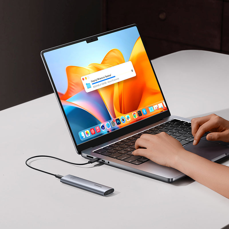 Person using a laptop with a USB drive connected, on a white surface.