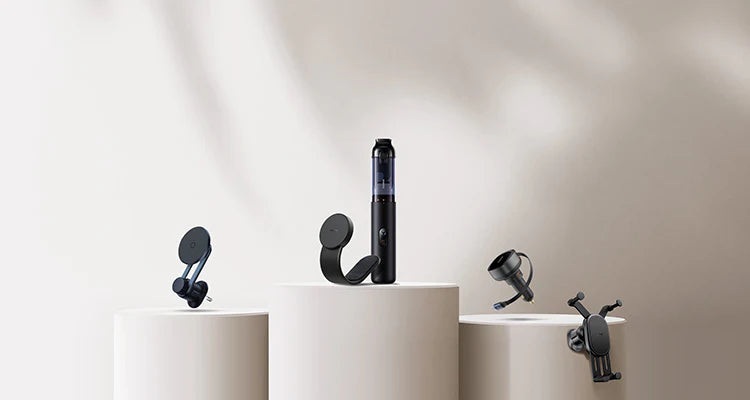 Black electronic devices on white cylindrical stands against a neutral background