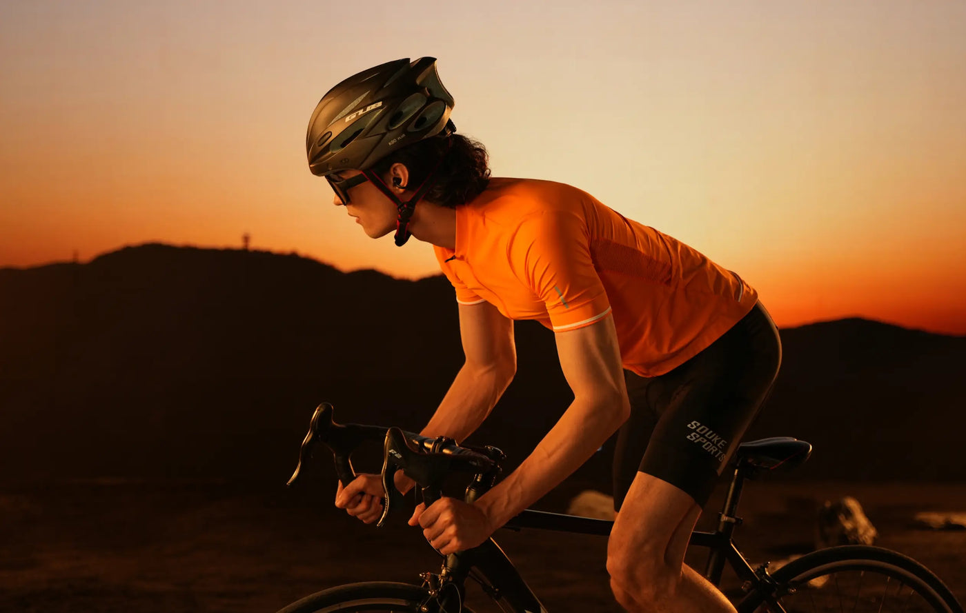 Person cycling at sunset with a warm orange sky